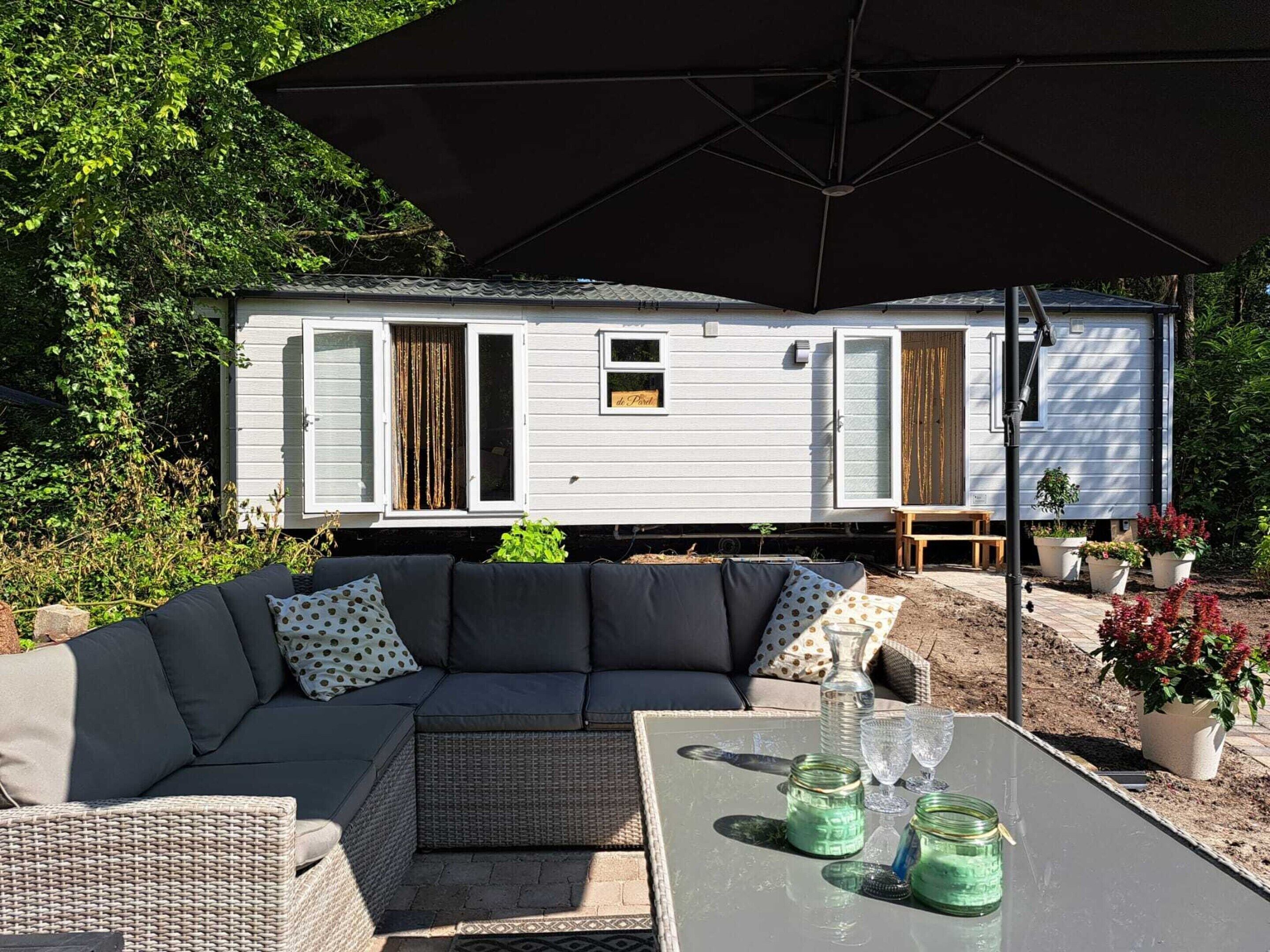 A mobile home with a patio area featuring a sofa, table, and potted plants.