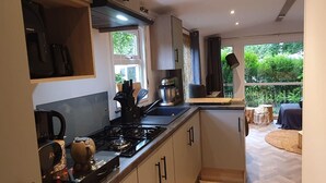 A compact kitchen with a gas stove, coffee maker, and a view of the outdoors through a window. - Nice Holiday Home in Hattemerbroek (Hattemerbroek)