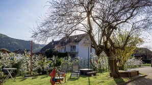 A residential area with a house, a tree, and outdoor furniture. - Apartment 'Hirschblick' with Mountain View, Shared Terrace and Wi-Fi (Haslach im Kinzigtal)