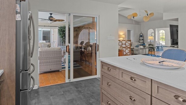 Eine moderne Küche mit Kühlschrank, ein Essbereich mit Tisch und Stühlen sowie eine Schiebetür zu einer Außenpatio.
