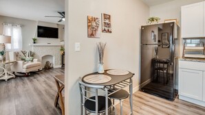 A modern kitchen with a refrigerator, dining table, and chairs. - Walking Distance to Downtown Wichita | In Unit W/D (Wichita)