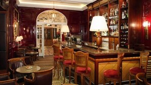 A bar area with wooden furniture, a bar counter, and a well-stocked liquor shelf. - The Goring (London)