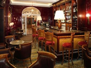A bar area with wooden furniture, a bar counter, and a well-stocked liquor shelf.
