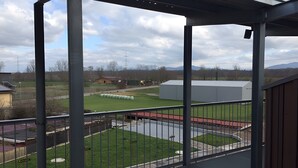 A covered outdoor area with a metal railing, a grassy field, and a building in the background. - Apartment 'Chardonnay' with Balcony and Wi-Fi (Freiburg im Breisgau)