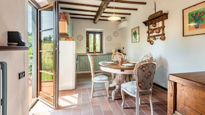 A kitchen with a dining table, chairs, and a hanging copper pot rack. - Holiday Home 'Uva' with Guest-Only Pool, Wi-Fi and Air Conditioning (San Gimignano)