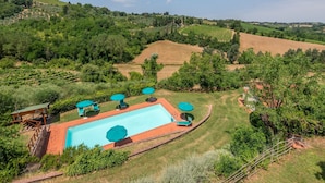 A swimming pool with lounge chairs and umbrellas, surrounded by a grassy area and vineyards. - Holiday Home 'Uva' with Guest-Only Pool, Wi-Fi and Air Conditioning (San Gimignano)