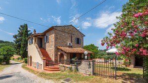 A stone house with a staircase, a fenced garden, and a clear sky. - "Volpe" Apartment with Pool Reserved for Guests, Wi-Fi, and Air Conditioning (San Gimignano)