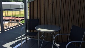A covered patio with a table and two chairs, a metal railing, and a view of a field and distant buildings. - Apartment '2 Spätburgunder' with Balcony and Wi-Fi (Freiburg im Breisgau)