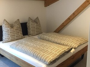A loft-style bedroom with a sloped ceiling, a wooden bed frame, and multiple pillows with geometric patterns. - Apartment 'Muskateller' with Balcony and Wi-Fi (Freiburg im Breisgau)