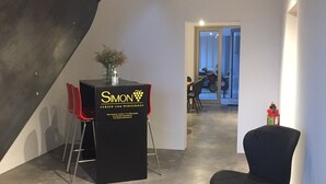 A modern interior with a black table displaying the 'Simon' logo, a staircase, and a hallway leading to another room.