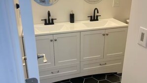 A bathroom with two sinks, a mirror, and a toilet. - Cottage 4 at MeadowView- near cave run lake! (Morehead)