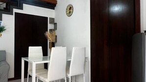 A dining area with a white table and chairs, a wooden ceiling, and a dark wooden door. - Giupa's home (Catania)