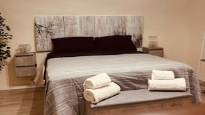 A hotel room with a large bed, a headboard with a tree design, two bedside tables, and a wooden floor. - Giupa's home (Catania)