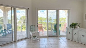 Una camera spaziosa con un balcone, un armadietto bianco e un piccolo tavolo con una pianta.
