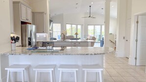 Un'ampia cucina con una grande isola, mobili bianchi e una ventola a soffitto.