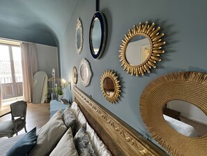 Una habitación con una cama, una silla y una pared decorada con varios espejos.