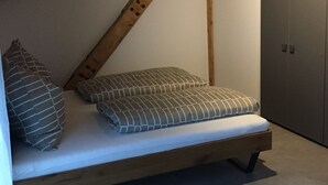 Ein Schlafzimmer im Loft-Stil mit Holzbalkendecke, einem Bett und zwei Kissen sowie einem Kleiderschrank.