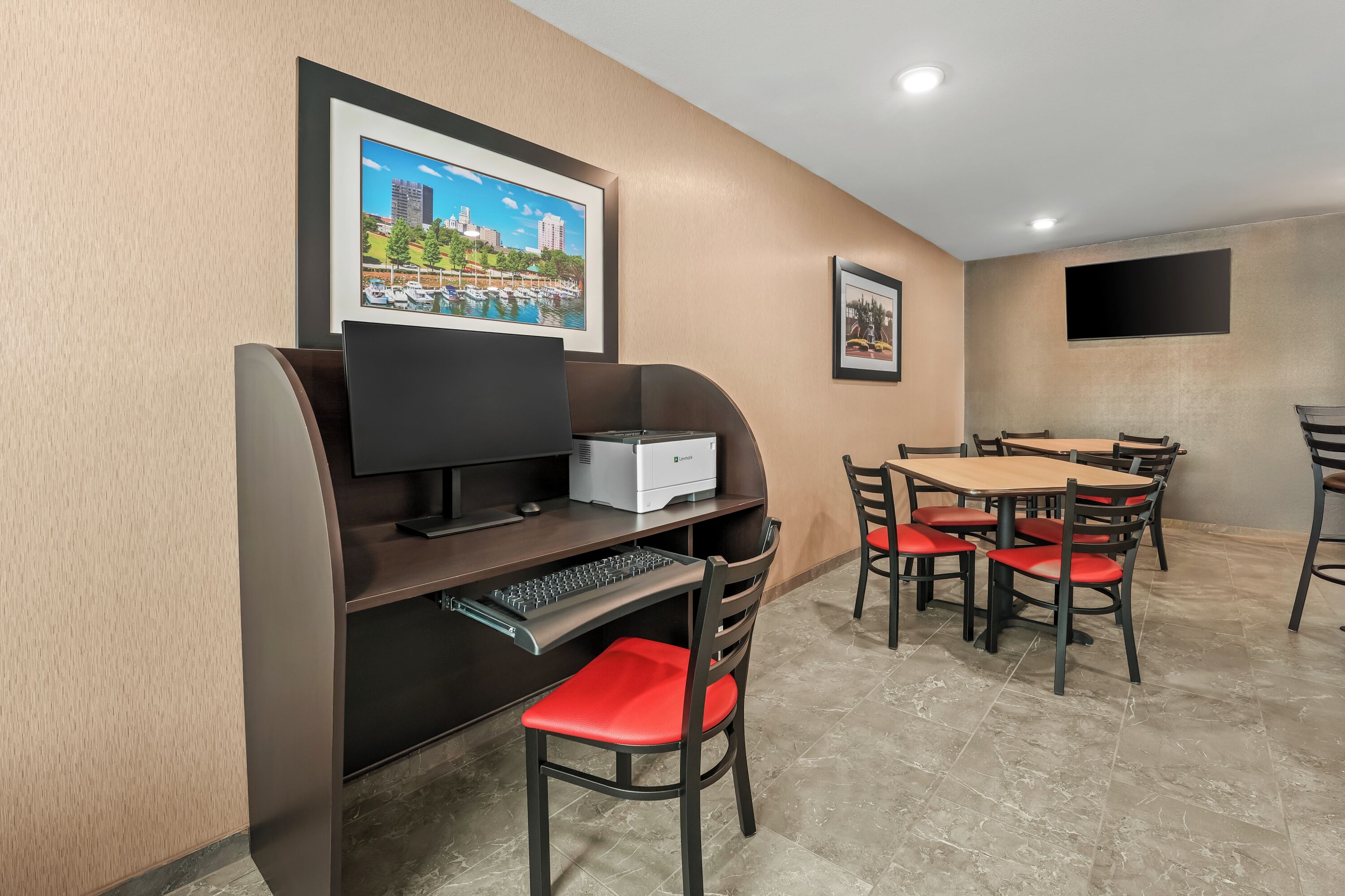 Ein Hotelzimmer mit Schreibtisch, Computer und Stühlen.