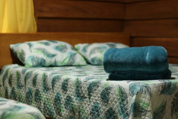 Una cama con colcha acolchada y dos almohadas con estampado de hojas.