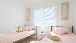 A bedroom with two beds, a window with blinds, and wall art. - New Build Smart Home 3 Bedroom (Sunnyvale)