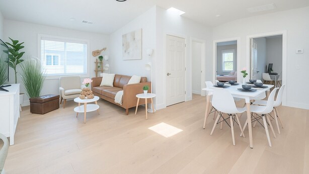 A modern living room with a sofa, coffee table, and dining area with chairs and a table. - New Build Smart Home 3 Bedroom (Sunnyvale)