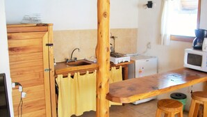 Una cocina con armarios de madera, un lavamanos, una estufa, un microondas y taburetes.