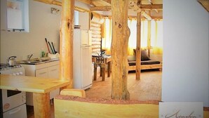 Una cocina rústica con vigas de madera, una zona de comedor con mesa de madera y un sofá.