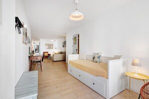 Un dormitorio con cama, mesita de noche, lámpara y vistas al salón.
