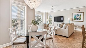 Un salon spacieux comprenant un coin repas, un ventilateur de plafond et un téléviseur.