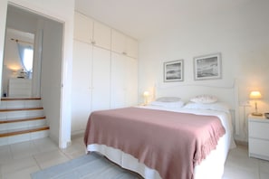 Une chambre à coucher avec un lit, une armoire, une table de chevet et un escalier.