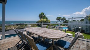 Une terrasse en bois avec une table de billard, des chaises et une vue sur l’océan.