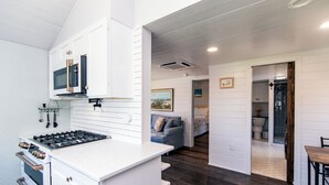 Una cocina moderna con armarios blancos, estufa a gas y microondas.