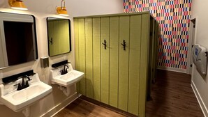 Une salle de bain avec deux lavabos, un miroir et un meuble de rangement vert.