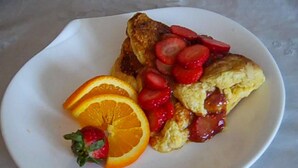 Ein Teller mit einem Gebäck, belegt mit Erdbeeren und Orangenscheiben.