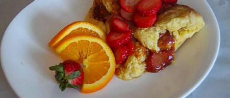 Un plato con un pastelito cubierto de fresas y rodajas de naranja.