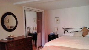 Ein Schlafzimmer mit Bett, Schminktisch, Nachttisch, Lampe und Spiegel.