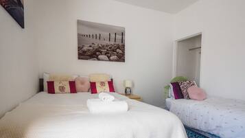 A hotel room with a large bed, a smaller bed, a painting on the wall, and a patterned rug.