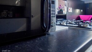 A microwave on a kitchen counter with a gas stove in the background. - 12 Cornwallis Lodge Family Room 2 (Stoke-on-Trent)