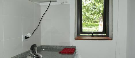 A kitchen with a kettle, a window, and a red towel on the counter.