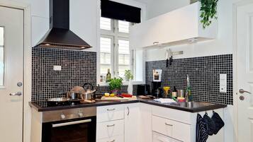 A modern kitchen with white cabinets, a black Bosch oven, a black range hood, and a black and white tiled backsplash.