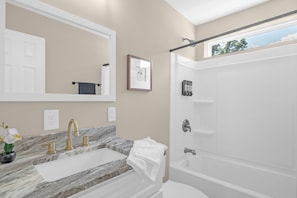 A bathroom with a marble sink, a large mirror, a framed picture, and a bathtub. - 3BR Greensboro Retreat •5 Mins from Downtown (Greensboro)
