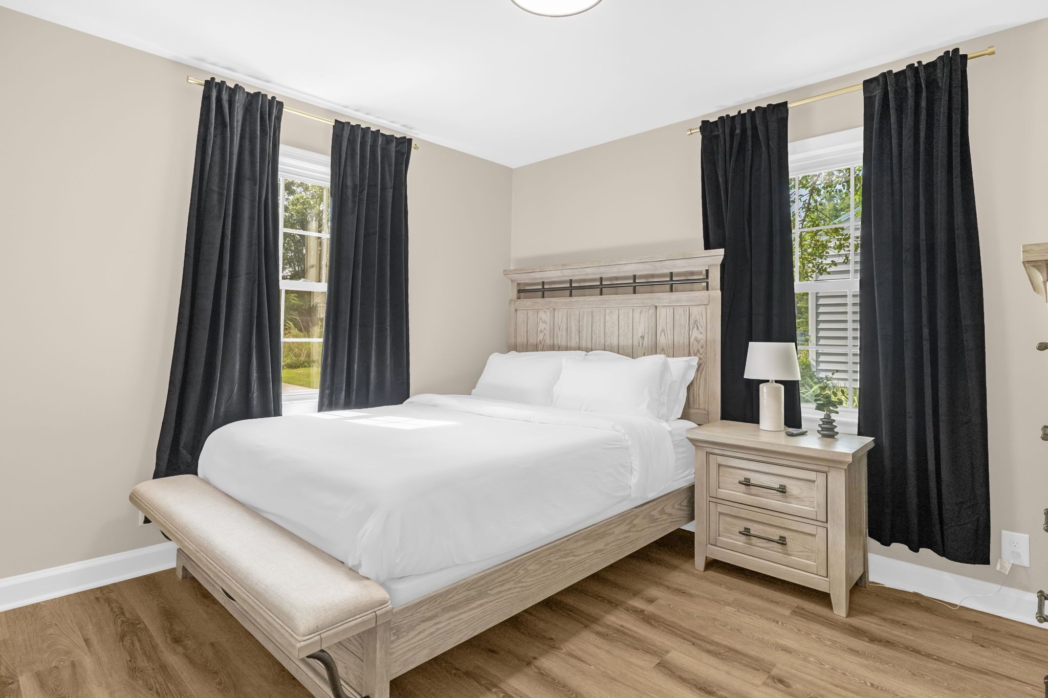 Une chambre à coucher avec un lit en bois, une table de chevet avec une lampe et un banc.