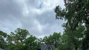 Een oprit die leidt naar een huis met een donker dak en een garage.
