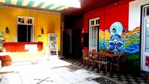 A building with a yellow exterior, a red door, and a mural on the wall. - Hipólito Raíz Hostel (San Rafael)