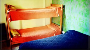 A bunk bed with two levels, a wooden frame, and a blue quilted mattress on the lower bunk. - Hipólito Raíz Hostel (San Rafael)