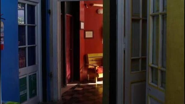 A narrow hallway with checkered flooring, leading to a room with a red wall and a door. - Hipólito Raíz Hostel (San Rafael)
