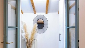 An open doorway leading to a room with a circular wall decoration, a tall vase with pampas grass, and wooden beams on the ceiling. - Apartment 'Nido Blu - Cosy Home' with Lake View, Wi-Fi and Air Conditioning (Belgirate)