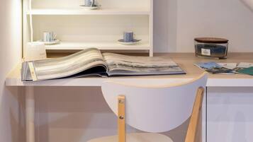 Un'area studio con scrivania, sedia, mensole piene di libri, una lampada e una piccola candela.