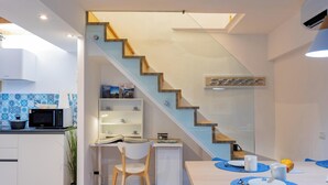 A modern kitchen with a built-in microwave, a dining area with a table and chairs, and a staircase with a glass railing. - Apartment 'Nido Blu - Cosy Home' with Lake View, Wi-Fi and Air Conditioning (Belgirate)