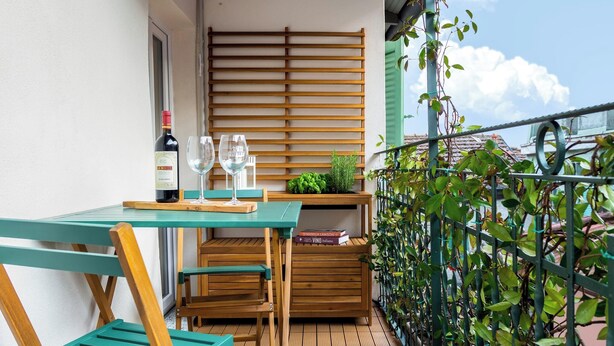 A small outdoor balcony with a wooden table, chairs, a bottle of wine, and a glass. - Apartment 'Nido Blu - Cosy Home' with Lake View, Wi-Fi and Air Conditioning (Belgirate)